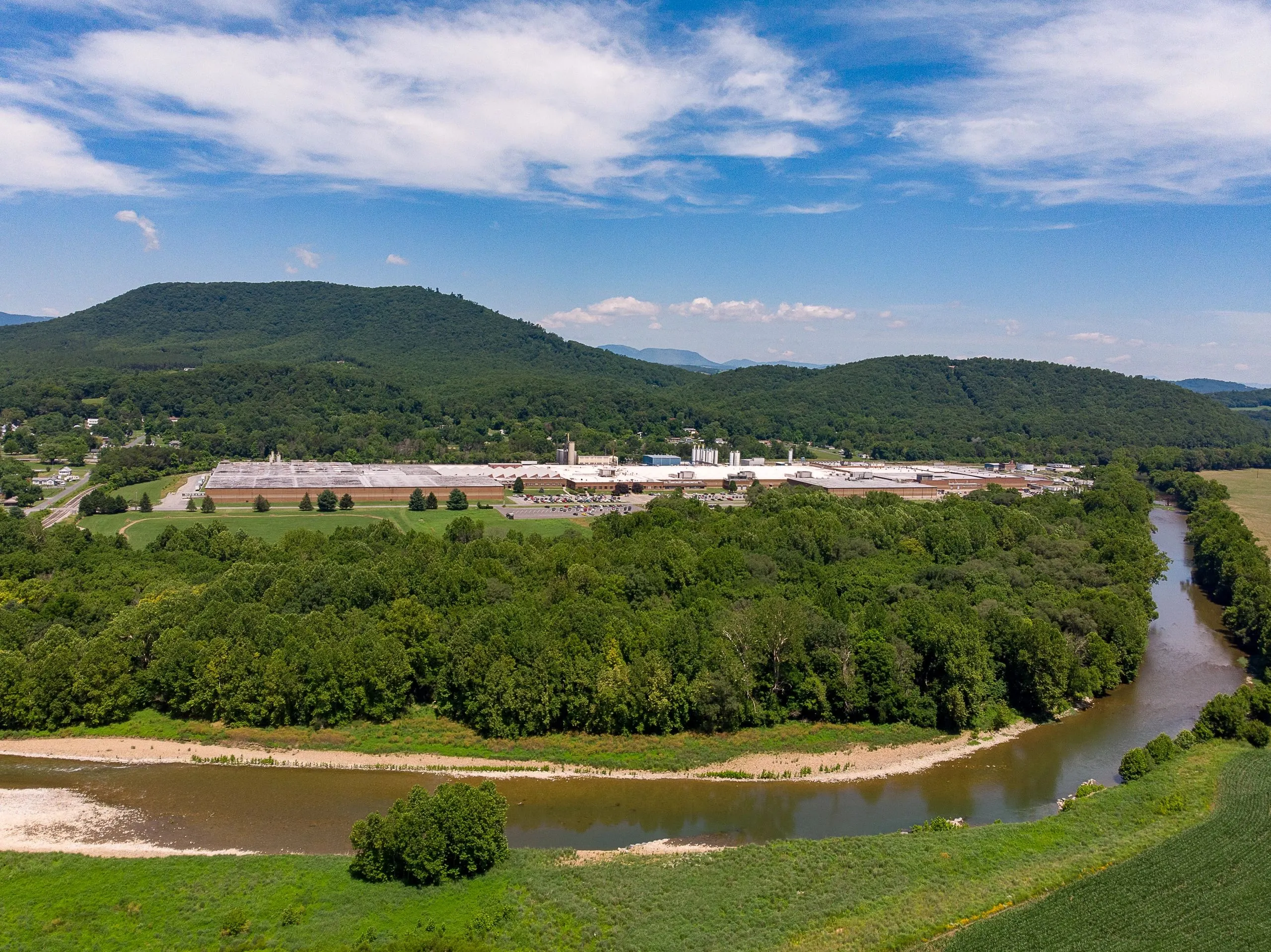 An aerial view of a large industrial mill complex set into a long curve of the river.